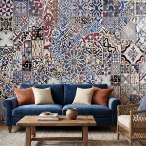 May include: A living room scene featuring a blue velvet sofa with orange and cream-colored throw pillows. A wooden coffee table holds books and a vase. The backdrop is a wall covered in patterned tiles in shades of blue, white, and red.