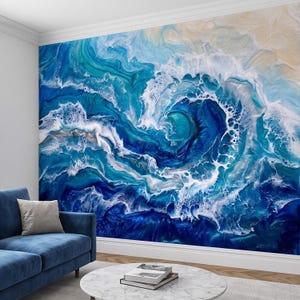 Op de afbeelding: Een grote muurschildering met een abstract fluid art ontwerp van oceaangolven in tinten diep marineblauw, helder turkoois en wit zeeschuim, met een zandbeige hoek, wat een dynamisch wervelend patroon over het gehele wandoppervlak creëert.