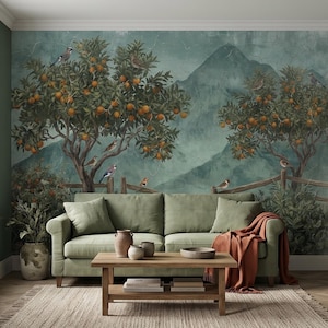 Könnte beinhalten: Ein salbeigrünes Sofa mit einer rostfarbenen Decke vor einer Wandtapete mit Orangenbäumen, Vögeln und Bergen. Ein hölzerner Couchtisch mit Keramikvasen steht im Vordergrund auf einem gewebten Teppich.
