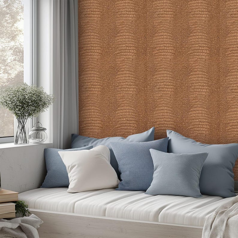 May include: A cozy window seat with a collection of pillows in shades of blue and white. The wall is covered in a textured, brown wallpaper. A vase of flowers sits on the windowsill, adding a touch of nature to the scene.