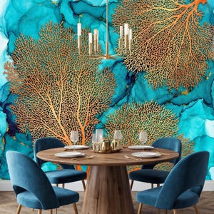 Peut inclure: Une salle à manger avec une table ronde en bois et des chaises en velours bleu. Le mur est orné d'une peinture murale turquoise et dorée avec des motifs coralliens. Un lustre doré est suspendu au-dessus.