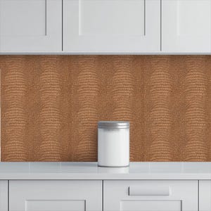 May include: A white kitchen canister with a silver lid sits on a white countertop. The background features a textured, brown backsplash with a reptile skin pattern. White cabinets are above.