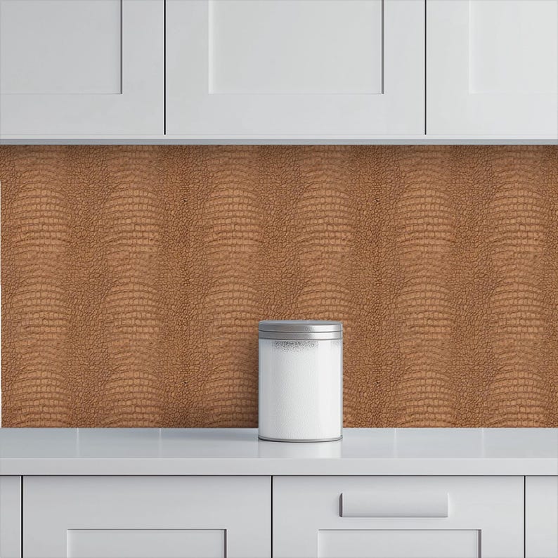 May include: A white kitchen canister with a silver lid sits on a white countertop. The background features a textured, brown backsplash with a reptile skin pattern. White cabinets are above.