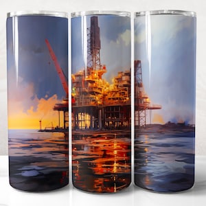 May include: A stainless steel tumbler with a colorful image of an offshore oil rig at sunset. The rig is lit up with yellow lights and is reflected in the water.