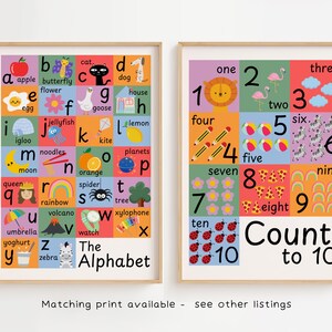 May include: Two framed educational prints. One features the alphabet with colorful illustrations for each letter. The other print displays numbers one through ten with corresponding images. Both prints have a wooden frame and are designed for children.