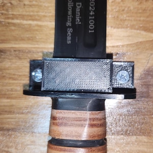 May include: A black knife with a brown wooden handle and a black plastic sheath. The knife has the text "Beltran, Daniel - 20305 - 20241001" and "Is and Following Seas" engraved on the blade.