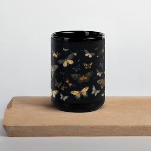 May include: Black ceramic mug with a pattern of colorful butterflies on a black background.