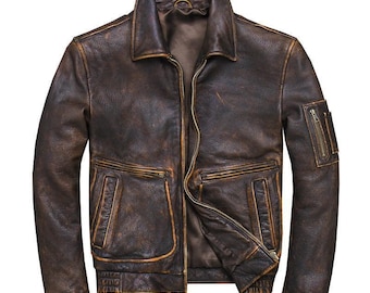May include: A brown leather bomber jacket with a distressed look. The jacket has a zipper closure, two front pockets, and a zippered pocket on the left sleeve.