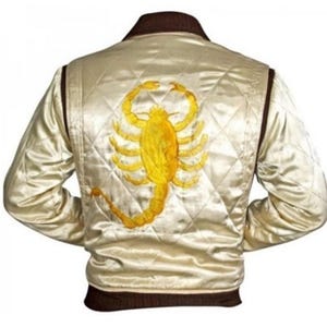 Puede incluir: Una chaqueta bomber de satén crema con cuello y puños marrones. La parte posterior de la chaqueta presenta un gran escorpión bordado en amarillo.