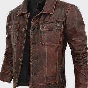 May include: A brown leather jacket with a classic design. The jacket features a collared neckline, button-down closure, and two chest pockets with button flaps. The jacket has a distressed, vintage look.