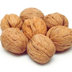 May include: A cluster of seven whole walnuts, each with a rough, textured, brown shell. The walnuts are arranged in a circular pattern against a white background, showcasing their natural form and color. The image highlights the organic texture of the nuts.