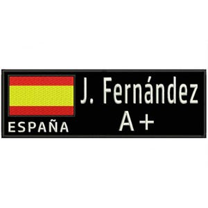 May include: Black rectangular patch with the Spanish flag on the left side, featuring red and yellow horizontal stripes. The text "ESPAÑA" is below the flag. The name "J. Fernández" and "A+" are on the right side.