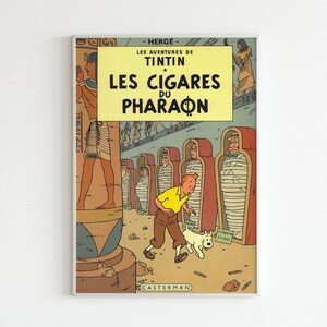 May include: A vintage comic book cover featuring Tintin and his dog Snowy in an Egyptian tomb. The cover is titled "Les Cigares du Pharaon" and features a yellow and red color scheme.