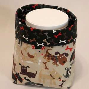 May include: A black and beige fabric storage bin with a white lid. The bin is decorated with a pattern of cartoon dogs and bones.