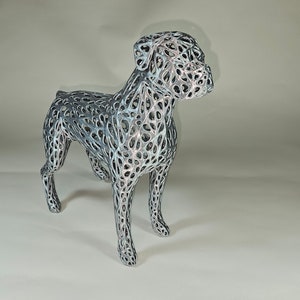 May include: A silver and black wireframe sculpture of a boxer dog. The sculpture is detailed and intricate, with a delicate wire mesh design.