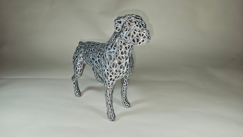 May include: A silver and black wireframe sculpture of a boxer dog. The sculpture is detailed and intricate, with a delicate wire mesh design.