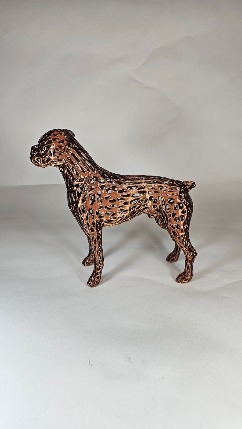 May include: A brown wireframe sculpture of a dog standing on a white surface. The sculpture is made of thin metal wires that are connected to form a three-dimensional shape.