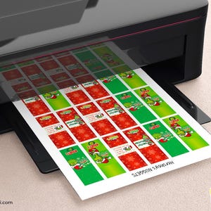 K&ouml;nnte beinhalten: Ein schwarzer Drucker druckt Bl&auml;tter mit weihnachtlichen Hershey's Nuggets-Etiketten. Die Etiketten haben rote und gr&uuml;ne Hintergr&uuml;nde mit Bildern einer Zeichentrickfigur und Schneeflocken. Der Text "Hershey's Nuggets" ist auf den Etiketten aufgedruckt.