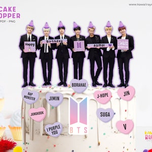 Puede incluir: Un topper de pastel con siete figuras de la banda de chicos surcoreana BTS, cada una sosteniendo un cartel con un mensaje diferente. Las figuras están de pie sobre un pastel decorado con corazones y el logotipo de la banda. El topper de pastel está impreso sobre un fondo blanco.