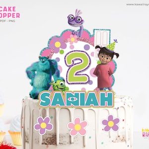 Könnte beinhalten: Ein rosa-weißer Tortendekor mit Figuren aus dem Film Monster AG. Der Dekor enthält Sulley, Mike, Boo und eine Nummer 2. Der Dekor enthält auch den Namen "Saniah" in türkisfarbenen Buchstaben.