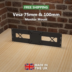 May include: A black Vesa 75mm & 100mm monitor mount. The mount has a rectangular shape with cut-out sections and a central mounting plate. The text "FREE SHIPPING" is at the top, and "MADE IN THE UK" is at the bottom.