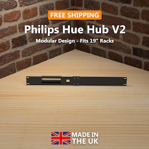 May include: A black Philips Hue Hub V2, designed to fit 19-inch racks. The product is shown on a light wood surface, with a brick wall backdrop. The image includes the text "FREE SHIPPING" and "MADE IN THE UK".