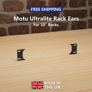 Puede incluir: Dos soportes de rack Motu Ultralite negros para racks de 25,4 cm se muestran sobre una superficie de madera clara. El texto "Motu Ultralite Rack Ears For 10" Racks" es visible. La frase "Free Shipping" está en un cuadro azul. También es visible "Made in the UK".