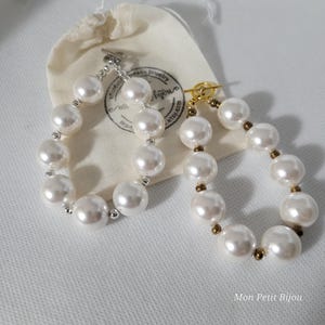 May include: Two bracelets featuring large white faux pearls separated by small metallic beads. One bracelet has silver-toned hardware with a toggle clasp, while the other has gold-toned hardware with a toggle clasp. A small fabric pouch is included.