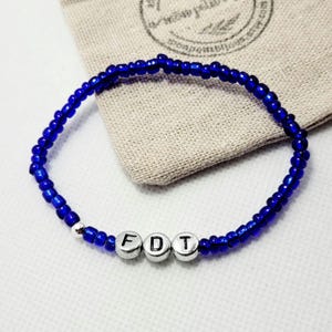 May include: A blue beaded bracelet with silver letter beads spelling out "FDT".