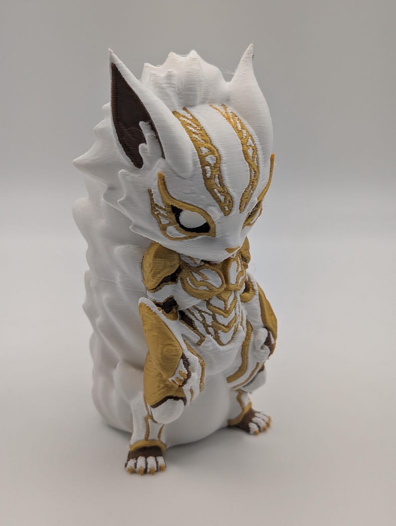 Pu&ograve; includere: Una statuetta stampata in 3D di una creatura stilizzata con armatura bianca e dorata. La figura presenta orecchie a punta con accenti marrone scuro, una criniera testurizzata e intricati motivi dorati sul petto, sul viso e sugli arti.