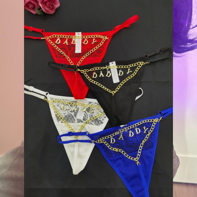 Pode incluir: Quatro pares de lingerie com renda delicada e correntes douradas. As correntes t&ecirc;m a palavra "Daddy" escrita nelas. A lingerie &eacute; vermelha, preta, branca e azul.