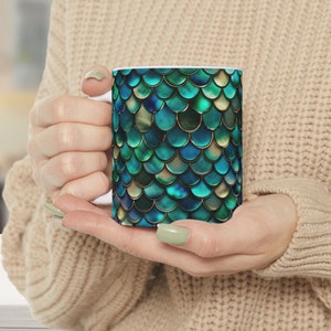 May include: A white ceramic mug with a teal and gold mermaid scale pattern.
