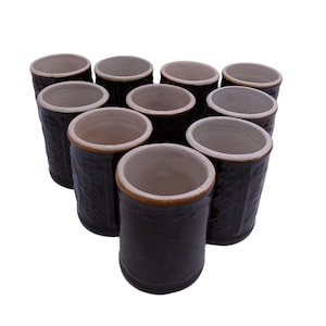 Könnte beinhalten: Zehn braune Keramikbecher mit weißen Innenräumen. Die Becher sind in Dreiecksform angeordnet.