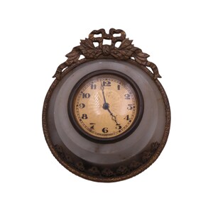 May include: A vintage clock with a decorative ornate frame. The clock face is white with black Roman numeral markings and black hands.
