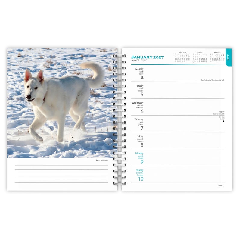 May include: A spiral-bound planner open to January 2027. The left page features a white dog running through snow. The right page displays a weekly calendar layout with the text January 2027, listing days from Monday the 4th to Sunday the 10th.