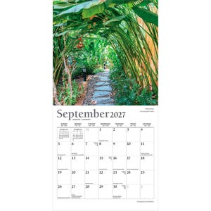 Pu&ograve; includere: Una pagina di calendario da parete per settembre 2027 con una fotografia di un sentiero in pietra che si snoda attraverso un rigoglioso giardino verde con piante alte e alberi. La griglia del calendario mostra i giorni con testi piccoli.