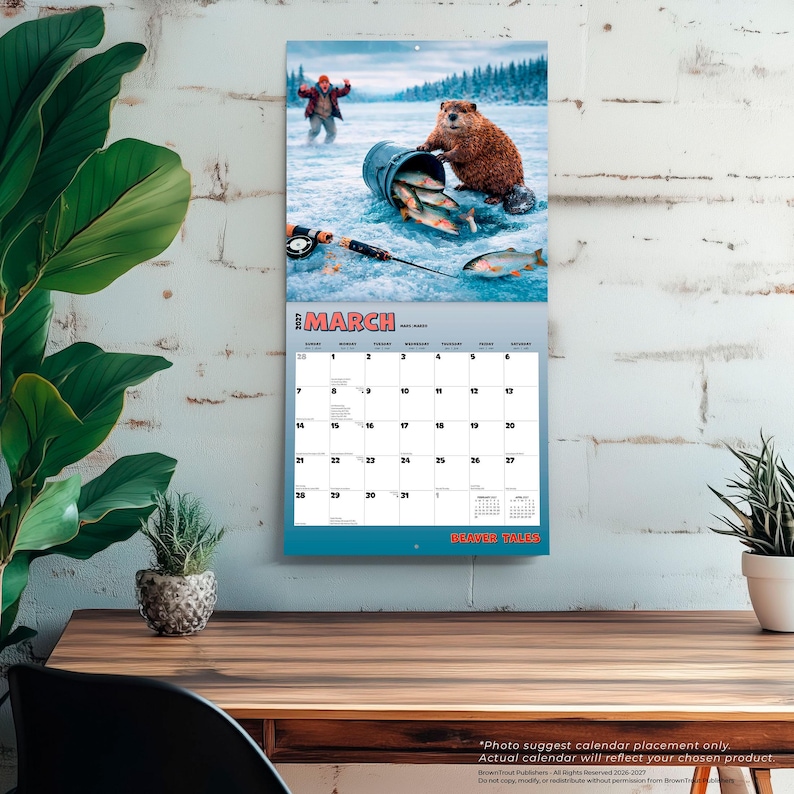 May include: A 2027 wall calendar for the month of March featuring a beaver on a frozen lake with a blue bucket of fish and a fishing rod. The calendar grid displays the days of the month with the title March and the text Beaver Tales at the bottom.