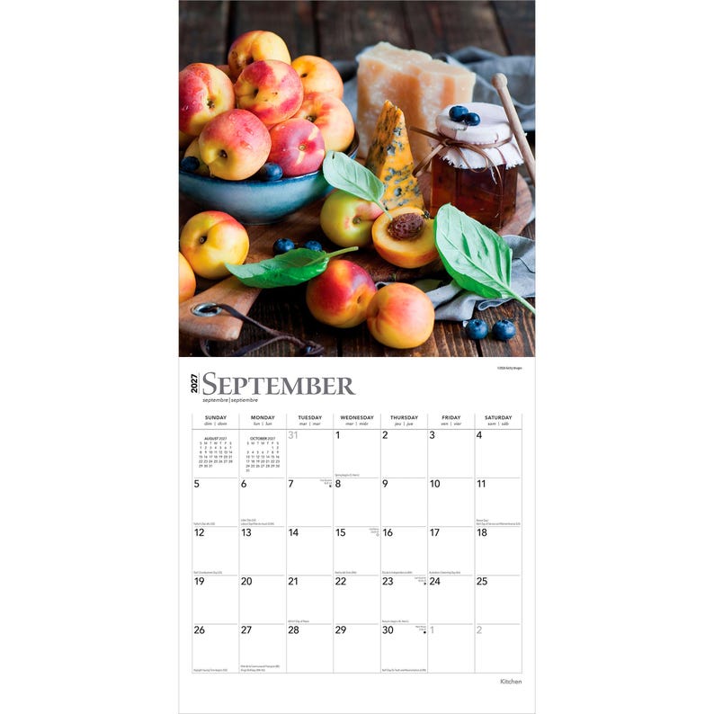 Puede incluir: Un calendario de pared para septiembre de 2027 con una imagen de melocotones frescos en un cuenco azul, un tarro de mermelada, un trozo de queso y hojas verdes. La parte inferior muestra una cuadr&iacute;cula para el mes con fechas del 1 al 30.