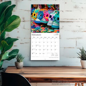 Puede incluir: Un calendario de pared para el mes de marzo de 2027 que presenta una fotograf&iacute;a de coloridas calaveras de az&uacute;car decorativas. La cuadr&iacute;cula del calendario muestra los d&iacute;as de la semana en espa&ntilde;ol, con el t&iacute;tulo MARZO impreso en la parte superior.