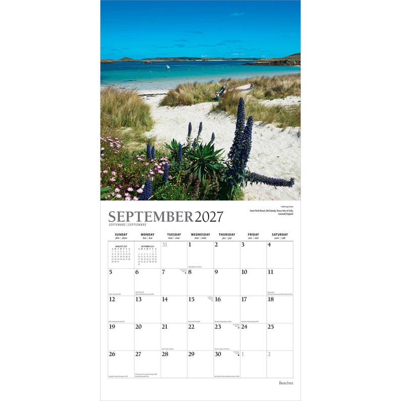 May include: A wall calendar for September 2027 featuring a photograph of a sandy beach path with tall dune grass, purple wildflowers, and a small boat near the turquoise water. The calendar grid displays the month, days, and dates clearly.