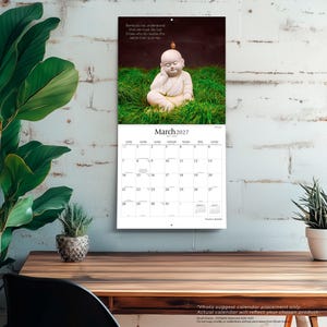 May include: A wall calendar for March 2027 featuring a photograph of a small white Buddha statue sitting in green grass with a tiny bird on its head. The text reads: Some do not understand that we must die, but those who do realize this settle their quarrels.