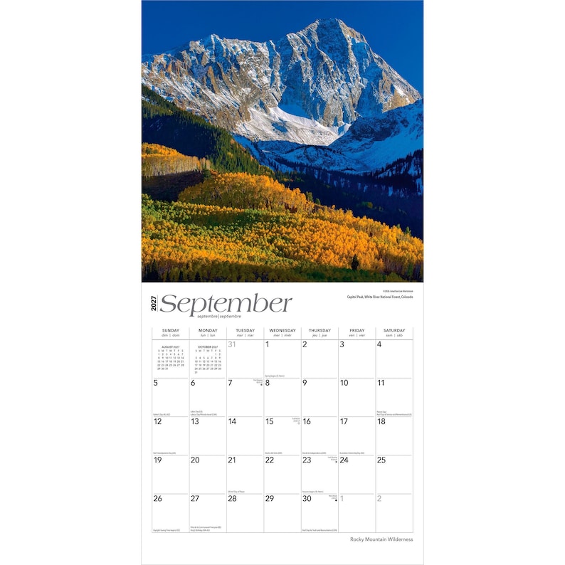 May include: A 2027 wall calendar for the month of September featuring a photograph of a snow-capped mountain peak above a forest of golden autumn trees. The calendar grid displays the days of the month with black text on a white background.