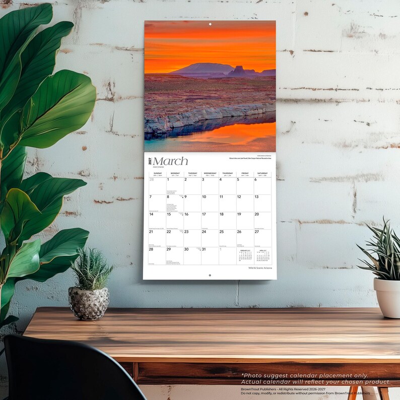May include: A wall calendar for March 2025 featuring a landscape photograph of a desert canyon at sunset with orange and purple skies reflecting in the water. The calendar grid displays the days of the month with small text for the previous and next months.