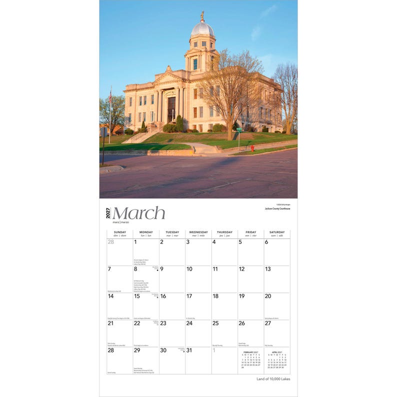 May include: A 2027 wall calendar page for March featuring a photograph of a stone courthouse with a central dome and clock tower under a clear blue sky. The calendar grid displays dates from the 1st to the 31st with small February and April calendars.