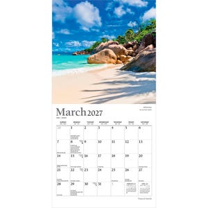 May include: A wall calendar for March 2027 featuring a photograph of a tropical beach with white sand, turquoise water, and large granite boulders under a blue sky with clouds. The calendar grid displays dates, days of the week, and holidays.