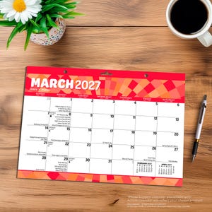 Puede incluir: Un calendario de pared para marzo de 2027 con un patr&oacute;n de fondo geom&eacute;trico en rojo y naranja. La cuadr&iacute;cula del calendario muestra las fechas del 1 al 31, con peque&ntilde;os calendarios de referencia para febrero y abril de 2027 en la esquina inferior.