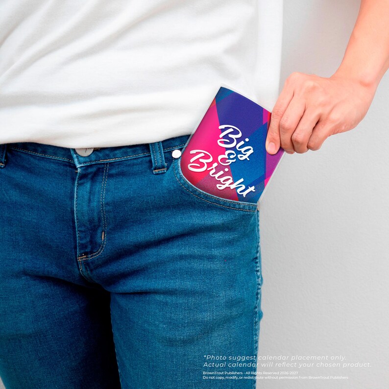 Puede incluir: Un calendario rectangular peque&ntilde;o con un fondo geom&eacute;trico vibrante en tonos azul, morado y rosa. El texto Big & Bright est&aacute; impreso en blanco con letra cursiva en el centro. El art&iacute;culo est&aacute; parcialmente metido en un bolsillo de mezclilla azul.
