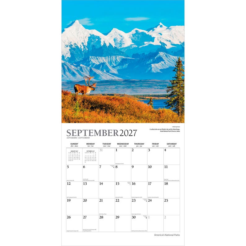 K&ouml;nnte beinhalten: Ein Wandkalender f&uuml;r September 2027 mit einer Fotografie eines Karibus, das in einem Feld aus orangefarbenem Herbstgestr&uuml;pp steht, vor schneebedeckten Bergen und blauem Himmel. Das Kalenderraster zeigt die Tage des Monats deutlich an.