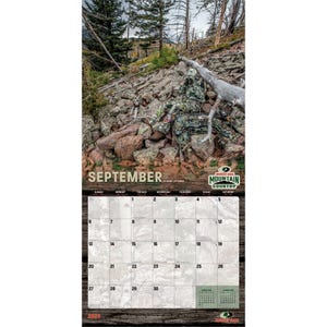 K&ouml;nnte beinhalten: Kalenderseite f&uuml;r September mit einer getarnten Person in einer felsigen, bewaldeten Landschaft. Das Kalenderraster ist unter dem Bild sichtbar, mit dem Monatsnamen. Das Logo von Mossy Oak Mountain Country ist ebenfalls vorhanden.