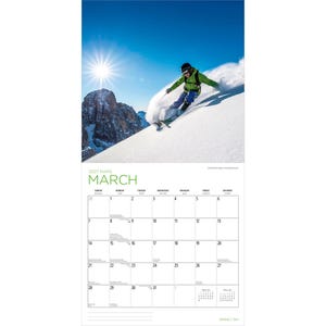 Op de afbeelding: Een wandkalender voor maart 2027 met een foto van een ski&euml;r in een felgroene jas en blauwe broek die door diepe sneeuw op een zonnige berghelling skiet onder een helderblauwe lucht met een opvallend zonnestraaleffect in de hoek.